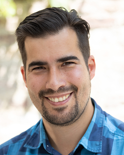 Mann in blau kariertem Hemd vor hellem Hintergrund l&auml;chelt freundlich in die Kamera